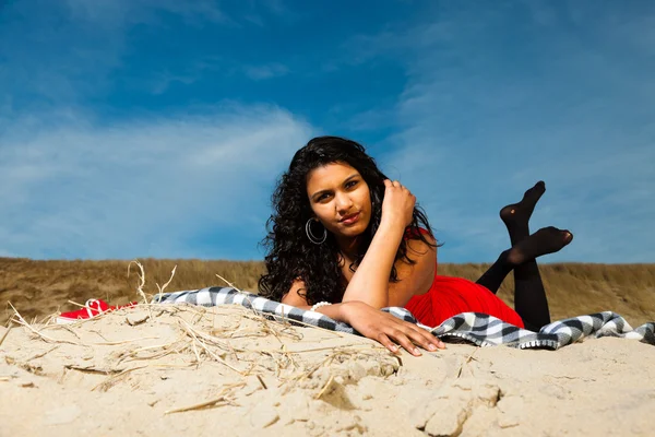 Indisk flicka med långt hår, klädd i rött på stranden i sommar — Stockfoto