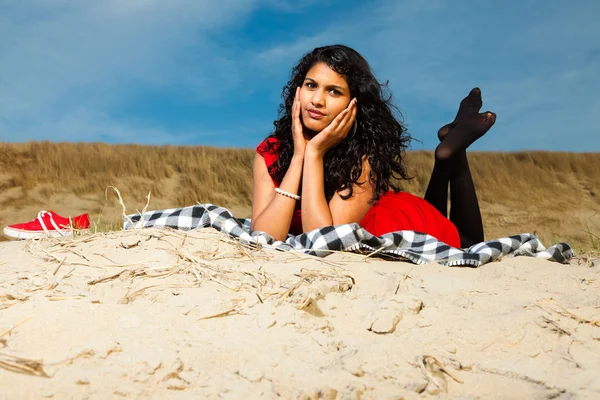 Indiase meisje met lange haren gekleed in het rood op het strand in de zomer — Stockfoto