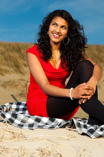 Indiase meisje met lange haren gekleed in het rood op het strand in de zomer — Stockfoto