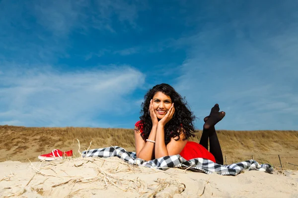 Индийская девушка с длинными волосами, одетая в красное на пляже летом — стоковое фото