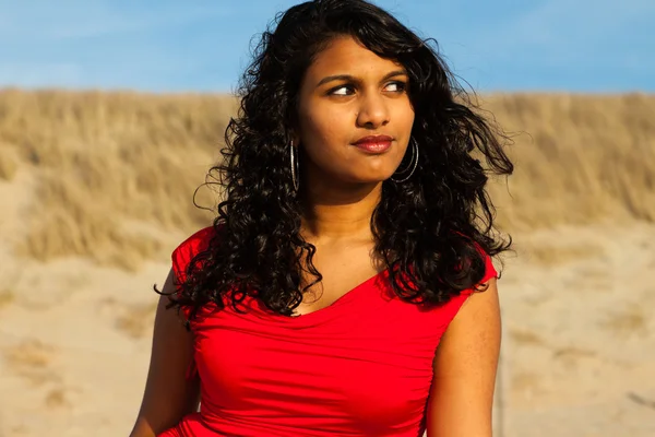 Ragazza indiana con i capelli lunghi vestita di rosso sulla spiaggia in estate — Foto Stock