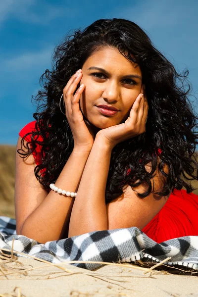 Indiase meisje met lange haren gekleed in het rood op het strand in de zomer — Stockfoto