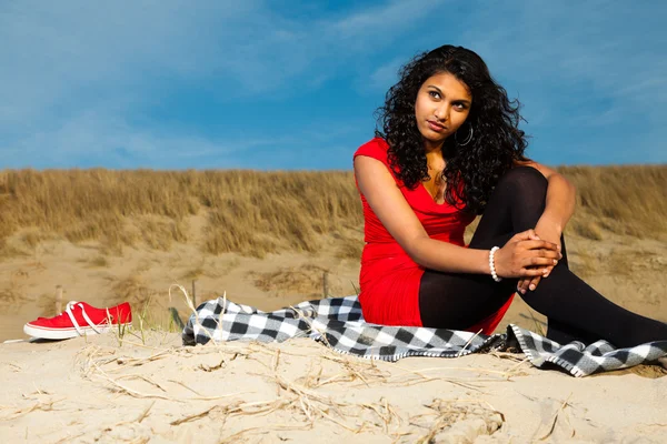 Indická dívka s dlouhými vlasy, oblečený v červené barvě na pláži v létě — Stock fotografie