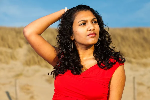 Indian girl with long hair dressed in red on the beach in summer — Stock Photo, Image