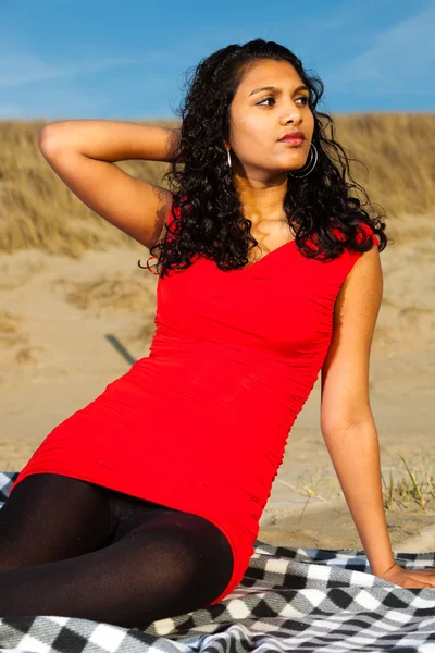 Indiase meisje met lange haren gekleed in het rood op het strand in de zomer — Stockfoto