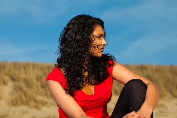 Ινδική κορίτσι με μακριά μαλλιά, ντυμένη στα κόκκινα στην παραλία το καλοκαίρι — Φωτογραφία Αρχείου