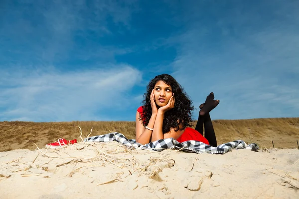 Indisk flicka med långt hår, klädd i rött på stranden i sommar — Stockfoto