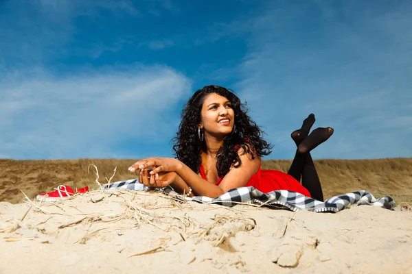 Indian girl with long hair dressed in red on the beach in summer