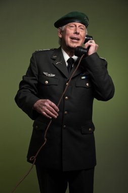 US military general wearing beret. Calling with phone. Studio po clipart