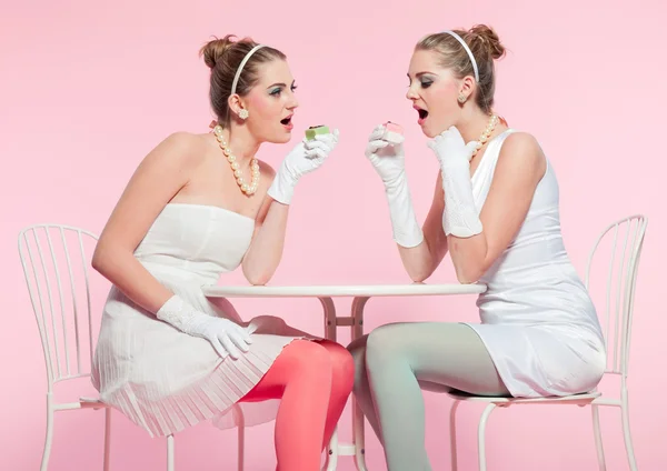 Dos chicas cabello rubio cincuenta estilo de moda comiendo pastel de taza . — Foto de Stock