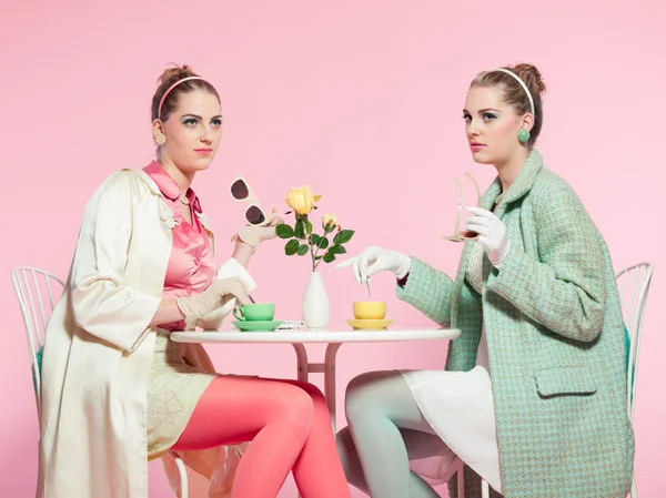 Duas meninas cabelo loiro dos anos cinquenta estilo de moda beber chá . — Fotografia de Stock