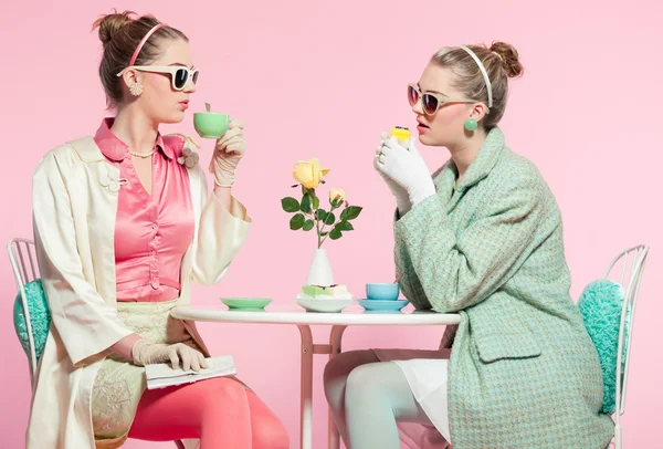 Duas meninas cabelo loiro dos anos cinquenta estilo de moda beber chá . — Fotografia de Stock