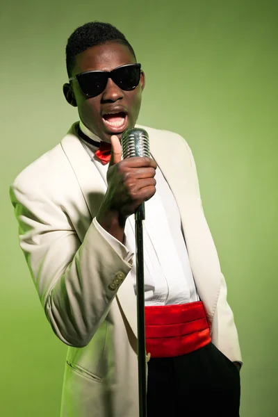 Éneklő fekete amerikai ember napszemüveget visel öltönyt. Vintage. — Stock Fotó