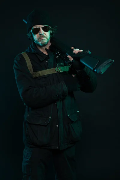 Sniper med skägg i svart anläggning gun. Studio skott. — Stockfoto