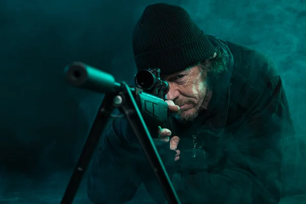 Sniper with beard in black holding gun. Studio shot. — Stock Photo, Image