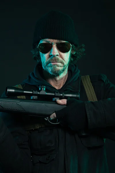 Sniper with beard in black holding gun. Studio shot. — Stock Photo, Image