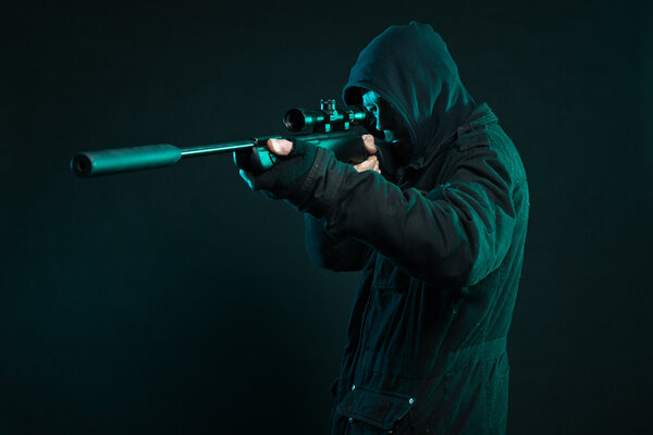 Sniper with beard in black holding gun. Studio shot.