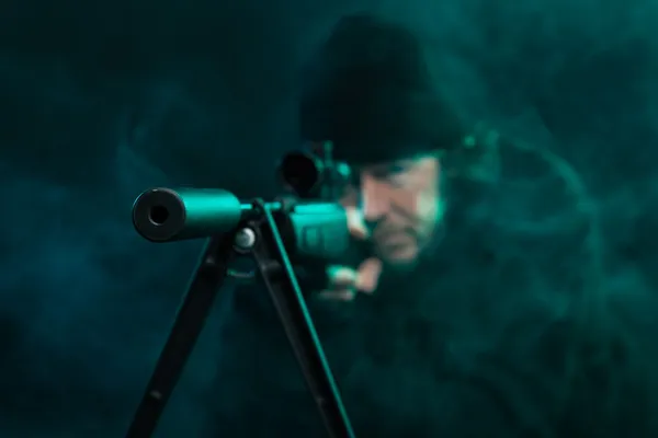 Sniper with beard in black holding gun. Studio shot. — Stock Photo, Image