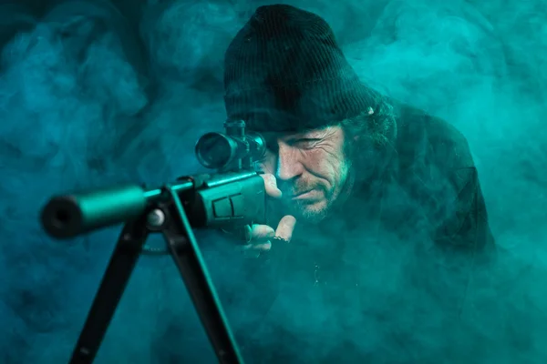 Sniper med skägg i svart anläggning gun. Studio skott. — Stockfoto