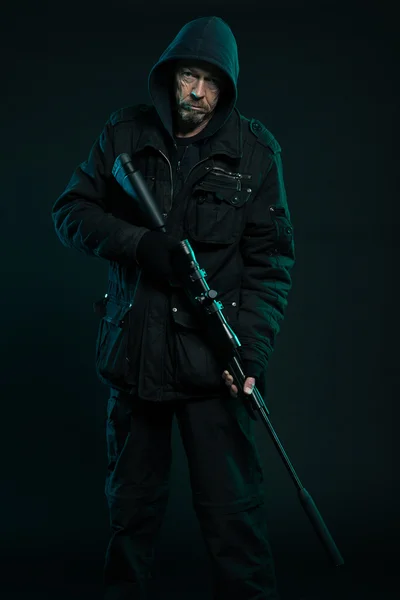 Σκοπευτής με γενειάδα σε μαύρο εκμετάλλευση πυροβόλο όπλο. Studio που γυρίστηκε. — Φωτογραφία Αρχείου
