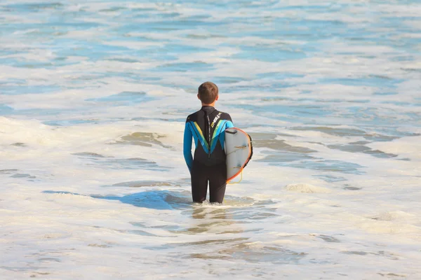 Fiatal szörfös áll a víz a malibui tengerparton. Amerikai Egyesült Államok. California. — Stock Fotó