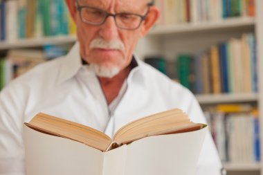 Komuta sizde kitap kitaplık önünde gözlüklü.