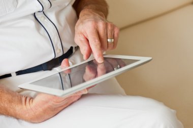 Komuta sizde tablet kullanarak eline. Beyaz koltukta oturan.