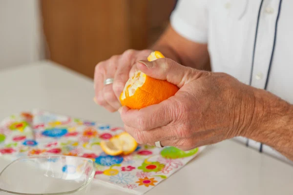 Primer plano de las manos del hombre mayor pelando naranja fresca . — Foto de Stock