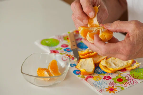 Primer plano de las manos del hombre mayor pelando naranja fresca . — Foto de Stock