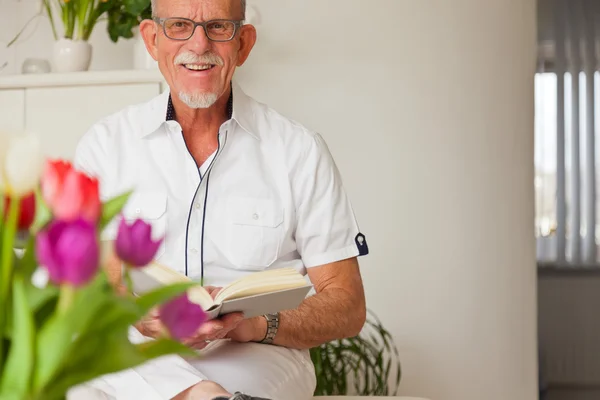 Uomo anziano con occhiali libro di lettura in soggiorno . — Foto Stock