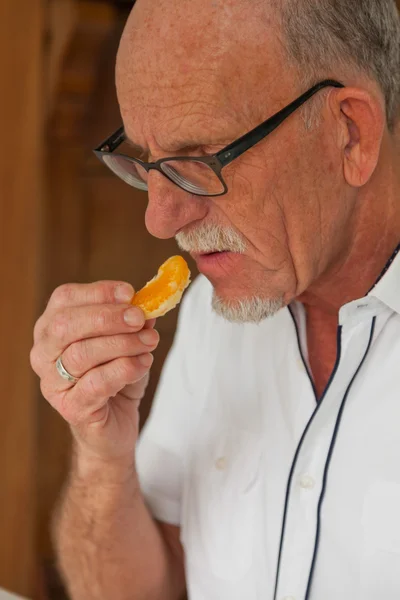 Hombre mayor comiendo plato de fruta fresca. Sentado en el salón . —  Fotos de Stock