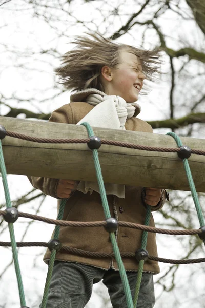 Rolig ung pojke med långt hår njuter av lekplatsen. — Stockfoto