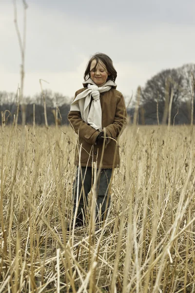 Playful funny young boy with long hair outdoor in wheat field. — Stock Photo, Image