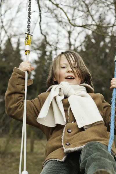 Rolig ung pojke med långt hår njuter av lekplatsen. — Stockfoto