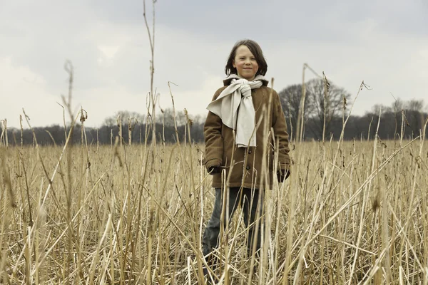 Playful funny young boy with long hair outdoor in wheat field. — Stock Photo, Image