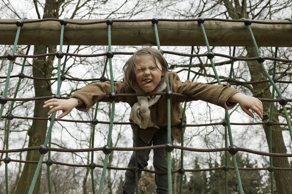 面白い遊び場を楽しんで長い髪の少年. — ストック写真