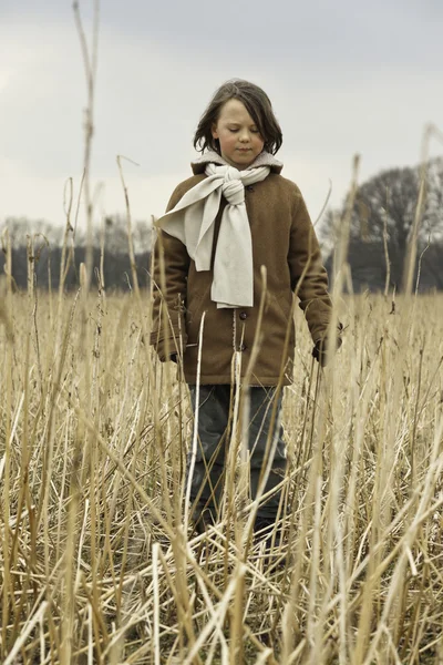 Speelse grappige jongen met lang haar buiten in tarweveld. — Stockfoto