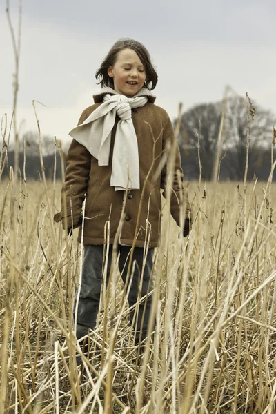Playful funny young boy with long hair outdoor in wheat field. — Stock Photo, Image