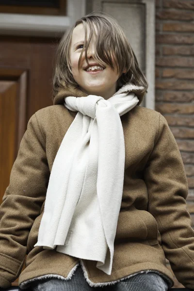 Verspielter lustiger kleiner Junge mit langen Haaren draußen vor dem Haus — Stockfoto