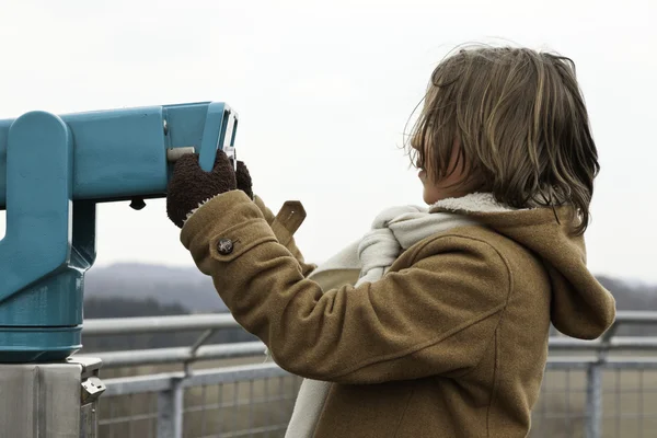 Speelse grappige jongen met lang haar bedrijf telescoop. — Stockfoto