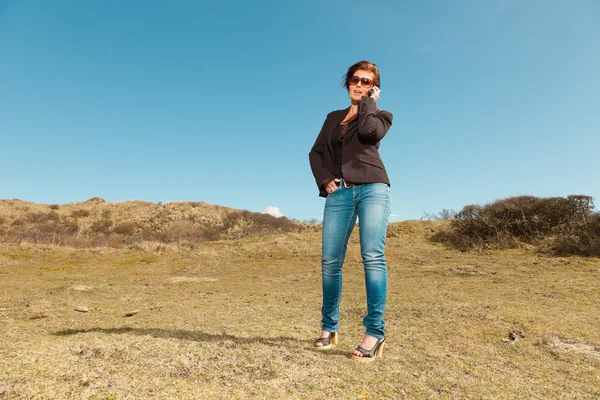 Bella donna bruna con occhiali da sole utilizzando il telefono cellulare. Prato — Foto Stock