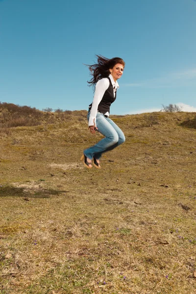 Feliz mujer morena bonita con pantalones vaqueros en el prado con sk azul —  Fotos de Stock