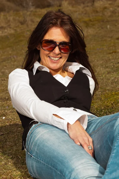 Glücklich hübsche brünette Frau trägt Jeans und Sonnenbrille draußen — Stockfoto