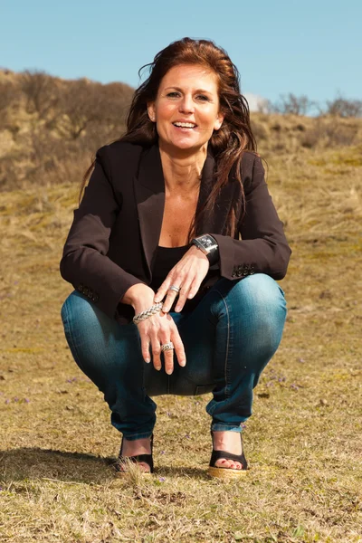 Smiling pretty brunette woman wearing brown jacket. Sitting in m — Stock Photo, Image