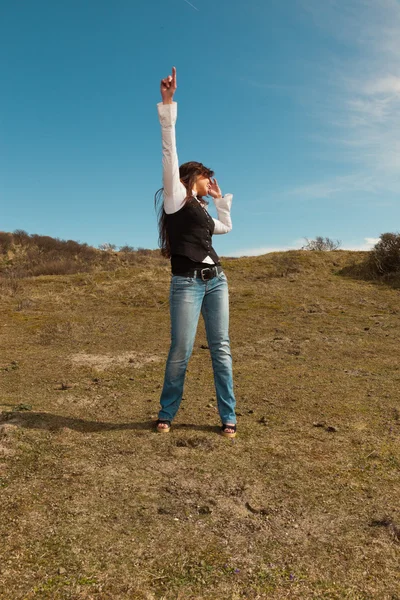 Gelukkig vrij brunette vrouw dragen van jeans in weiland met blauwe sk — Stockfoto