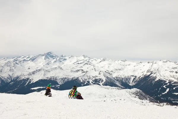 Snowboarder κάθεται στο χιόνι. τοπίο βραχώδες βουνό. — Φωτογραφία Αρχείου