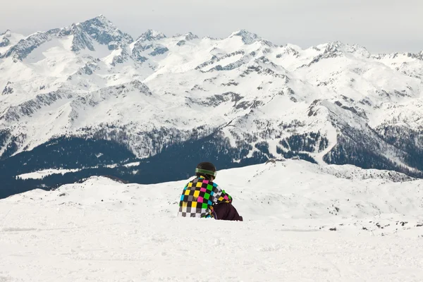 Snowboarder im Schnee sitzend. Felsige Berglandschaft. — Stockfoto