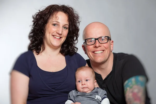 Happy couple holding their baby. Studio shot. — Stock Photo, Image