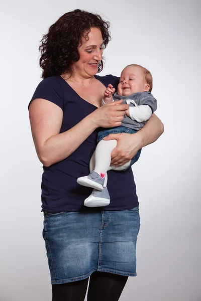Happy mother holding her baby in her arm. Studio shot. — Stock Photo, Image
