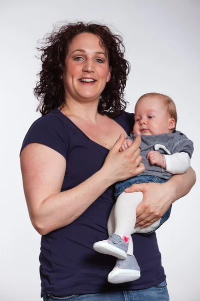 Feliz madre sosteniendo a su bebé en su brazo. Captura de estudio . —  Fotos de Stock